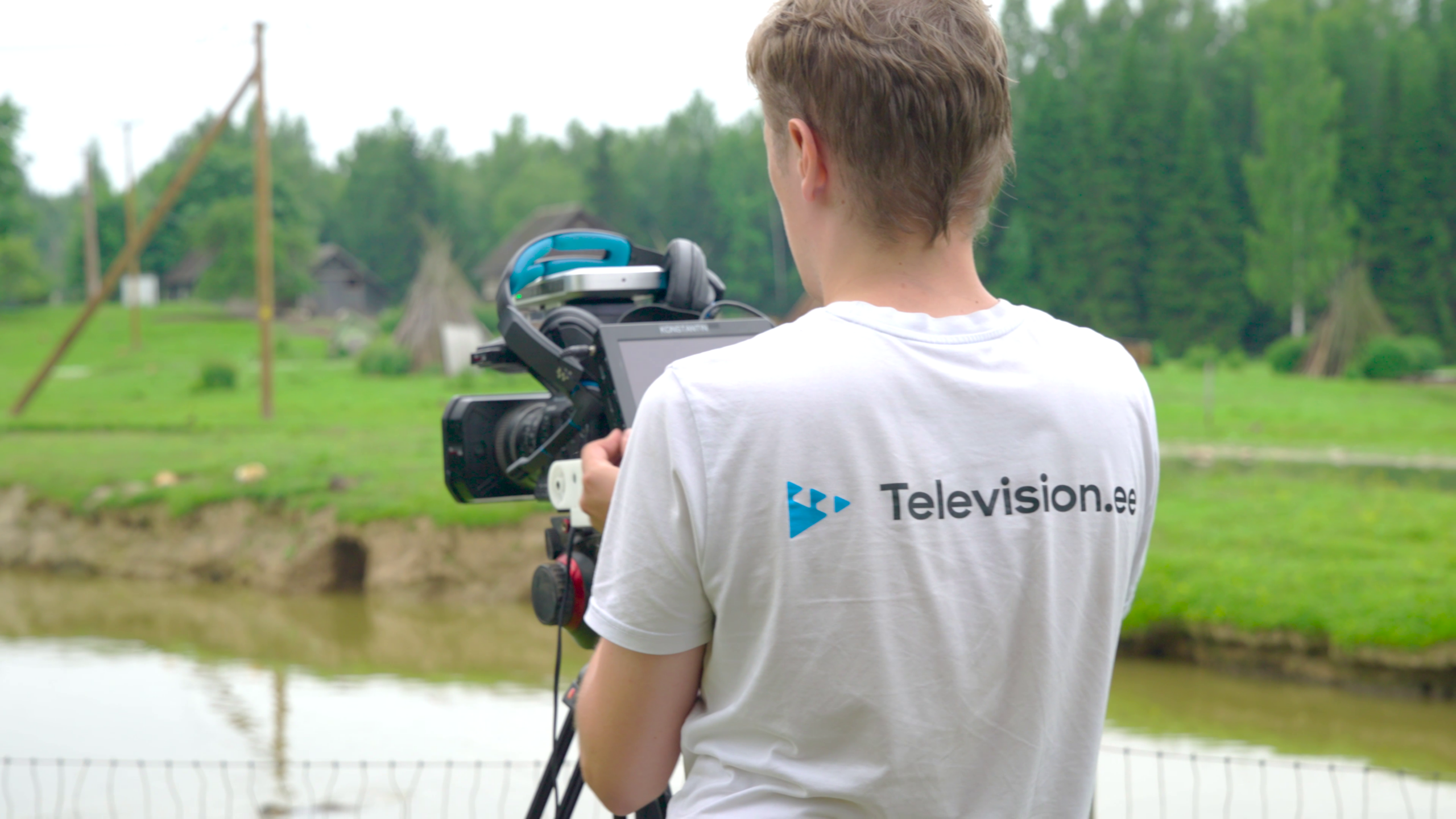Television.ee särgiga kaameraoperaator statiivikaamera taga veekogu ääres.